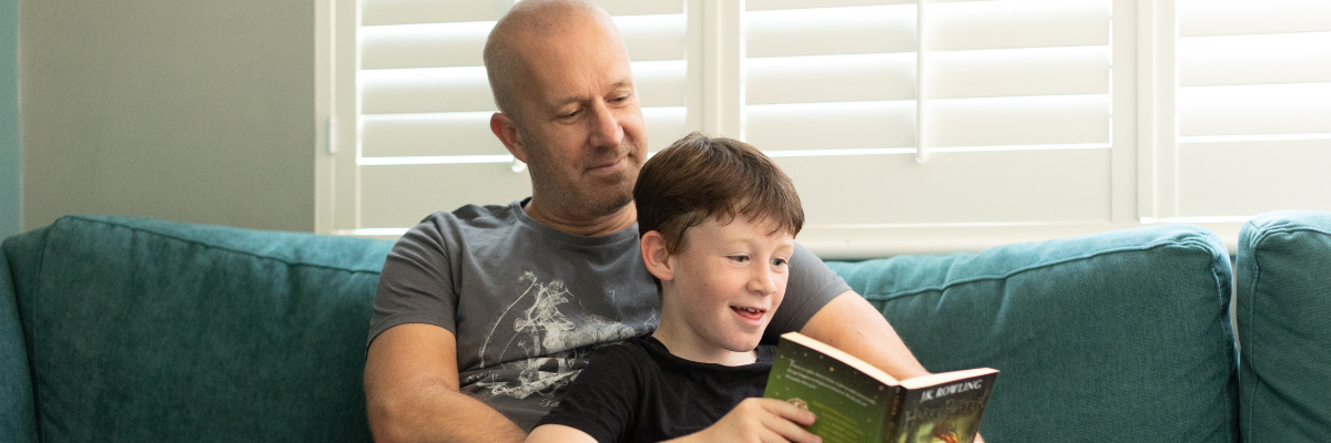 Dad and son reading happily on a sofa