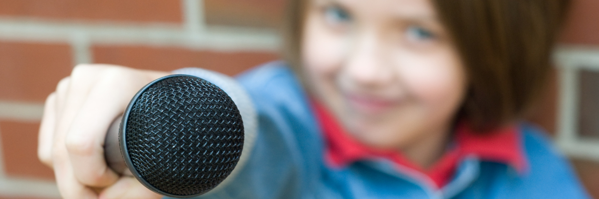 Small girl holding a microphone to interview someone
